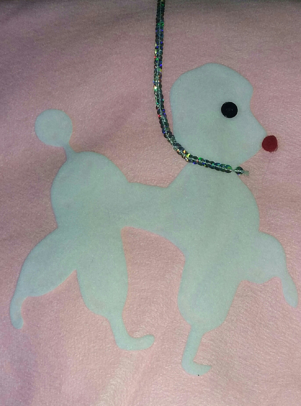 A pink 50's deluxe poodle skirt adult costume accessory, felt skirt with a poodle design and a decorative bow.